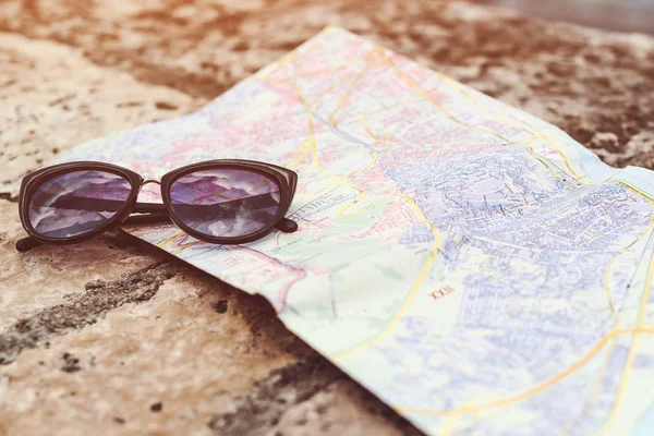 Acessórios de viagem no fundo do banco de pedra. Mapa do viajante e óculos de sol. Itens do viajante férias . — Fotografia de Stock