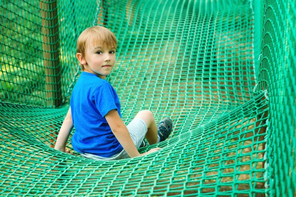 Liten glad pojke ha roligt i äventyrsparken. Barn som leker utomhus lekplats. — Stockfoto