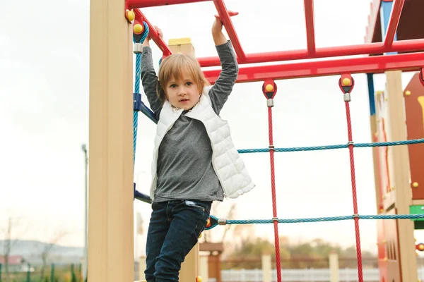 Nettes kleines Mädchen, das auf dem Schulhof-Spielplatz auf einem Kletternetz spielt. Kinder spielen und klettern im Freien. — Stockfoto