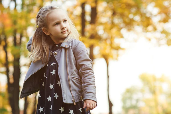 Fashionabla liten flicka leker med höst löv. Lyckligt barn utomhus. — Stockfoto