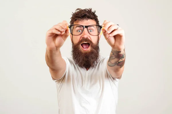 Homem barbudo excitado tocando os óculos e mantendo a boca aberta contra o fundo branco . — Fotografia de Stock