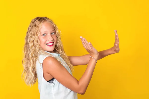 Feliz menina pré-adolescente alegre com sorriso perfeito se divertindo no fundo amarelo . — Fotografia de Stock