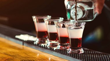 Barmen barda küçük bardakiçine güçlü alkollü içki döküyor. Gece kulübünde kırmızı çekimler.