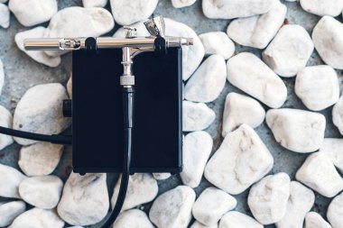 Makyaj için modern aerograf. Taşlara hava fırçası, kopya alanı. Profesyonel makyaj airbrush. Düz döşeme, üst görünüm.