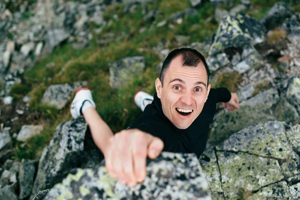 Joven escalando una pared empinada en la montaña. Escalada en roca deporte extremo. Hombre de turismo senderismo y escalada en las montañas . — Foto de Stock