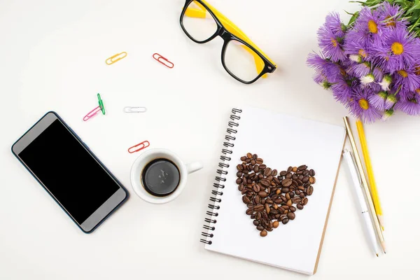 Plancha creativa con libro abierto, teléfono móvil, vasos, café y flores de verano en la mesa blanca . — Foto de Stock