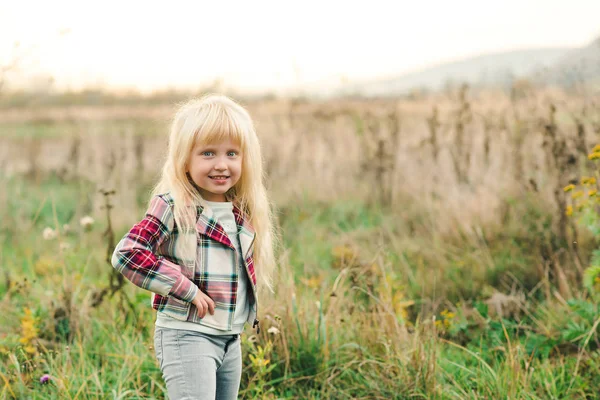 Niedliches kleines Mädchen mit langen blonden Haaren und erstaunlichen Augen auf Naturhintergrund. Mode stilvolles Kind im Freien. — Stockfoto