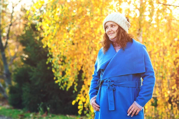 Belle femme d'automne à l'extérieur. La mode féminine. Jeune femme vêtue d'un manteau bleu et chapeau chaud, marchant dans le parc d'automne . — Photo