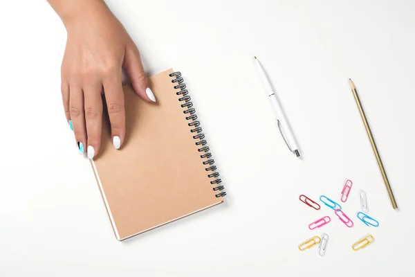 Kvinnlig hand skriva i en anteckningsbok vid skrivbordet. Översta vyn, kopiera utrymme. Vitt bord med planerings bok. — Stockfoto