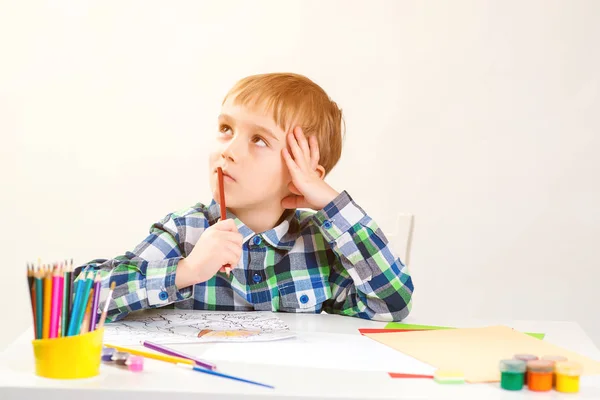 Niño pequeño dibujando en clase de arte. Un chico pensando en una nueva idea creativa. Lindo dibujo infantil preescolar en casa . — Foto de Stock