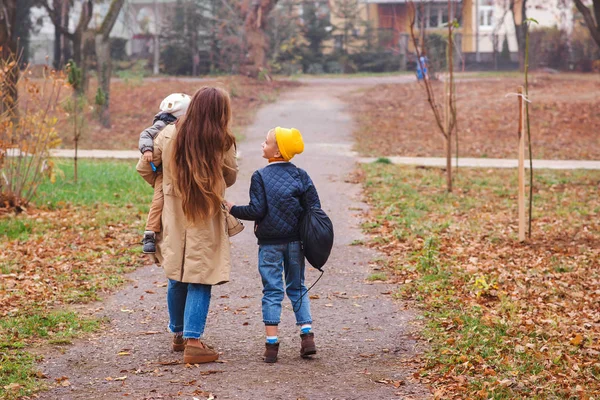 快乐的母亲和儿子上学和上幼儿园。母亲带着两个儿子在秋天散步. — 图库照片