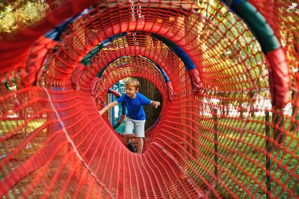 Happy little boy climbing rope obstacle activity on outdoors playground. Happy and healthy childhood. — Stock Photo, Image