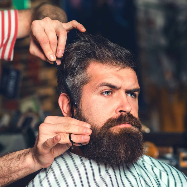 Cabeleireiro servindo cliente na barbearia. Homem barbudo brutal. Tesoura de barbeiro. Barbearia vintage — Fotografia de Stock