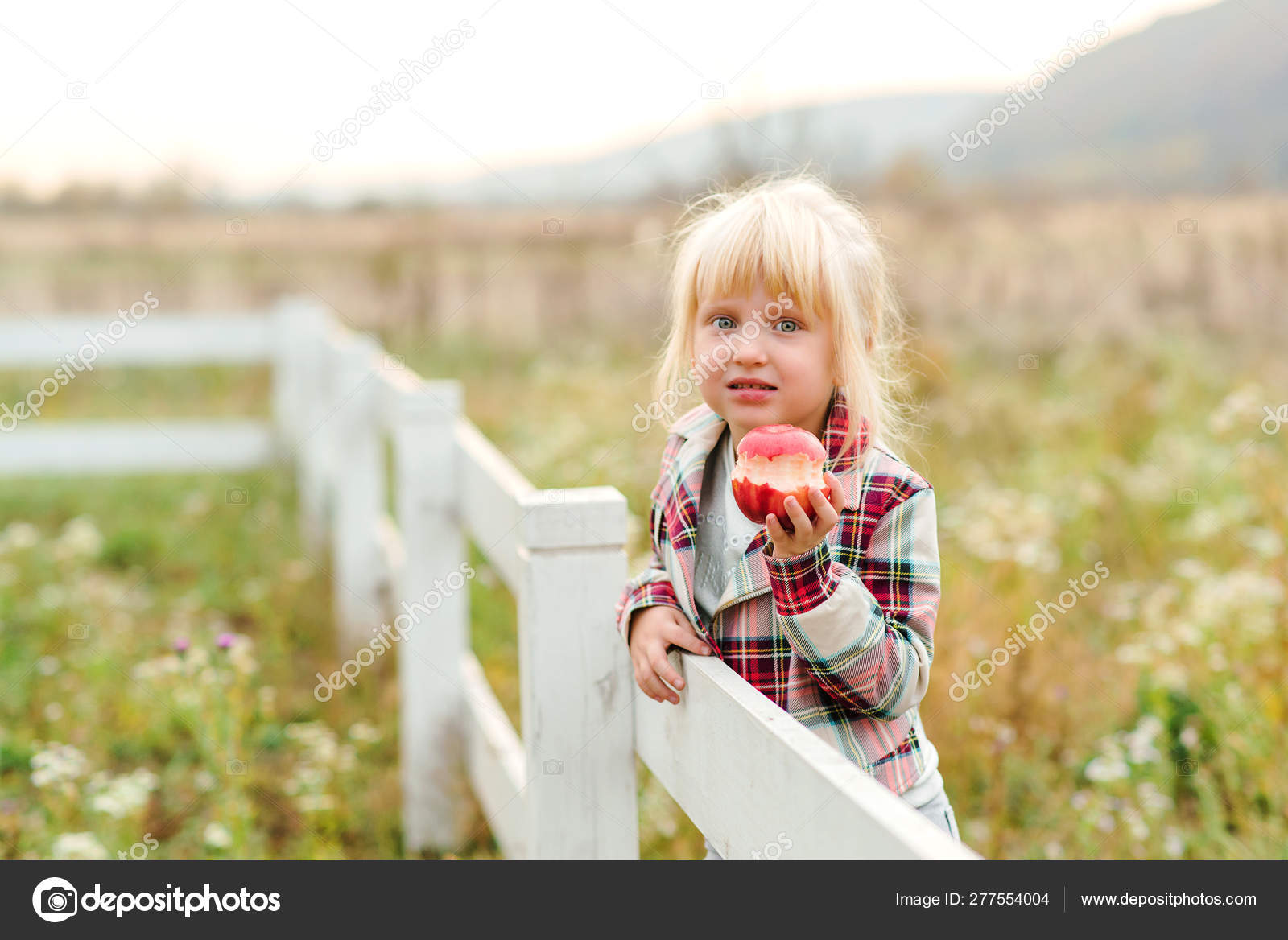 Happy Little Girl Eating Apple Outdoors Cute Child Girl On A Walk