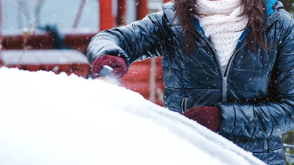 Lány takarítás autó a havon. Tiszta autó ablak hó. Téli szélvédő autótisztítás. Hóeltakarítás ablakból. — Stock Fotó