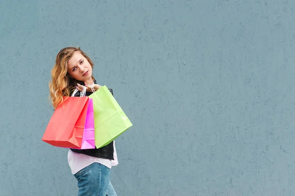 Chica feliz hace compras en una tienda en línea contra un fondo de pared gris. Copia espacio para texto o diseño. Ventas estacionales . — Foto de Stock