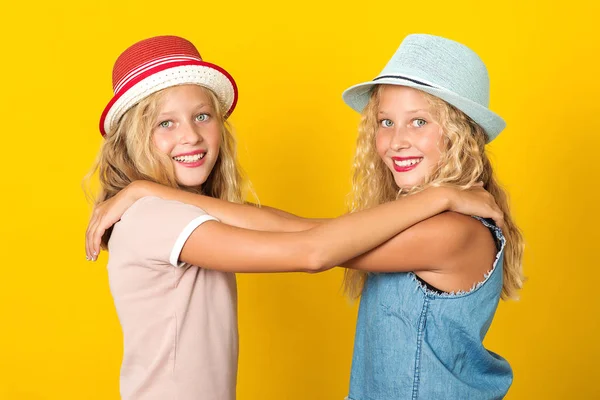 Chicas felices con sombrero de verano, posando sobre fondo amarillo. Hermanas guapas gemelas abrazándose y sonriendo. Moda de verano . — Foto de Stock