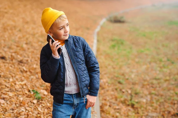 가을에 산책하는 세련 된 소년. 밖에서 휴대 전화로 얘기하는 소년. 가을 패션 컨셉. 사람들, 생활 습관을 바꾸는 기술 개념 — 스톡 사진