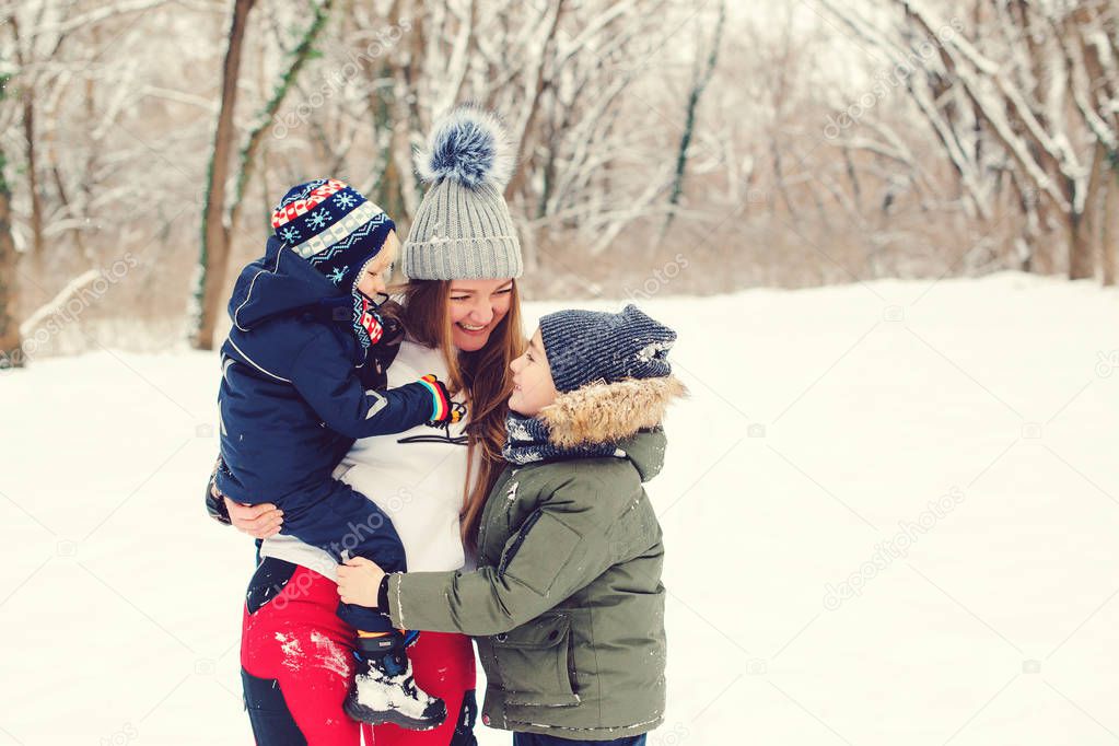 Happy mother hugging her cute sons, smiling and laughing. Winter fashion. Christmas and winter holidays. 