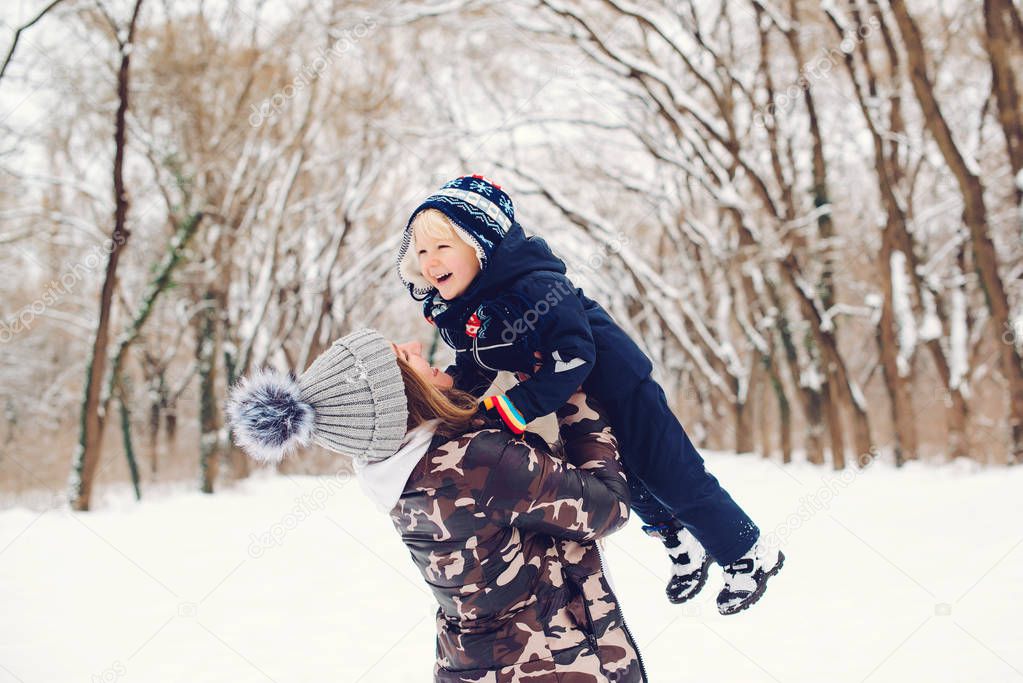 Happy mother and child having fun on snowy winter walk in nature. Frost winter season. Happy loving family.