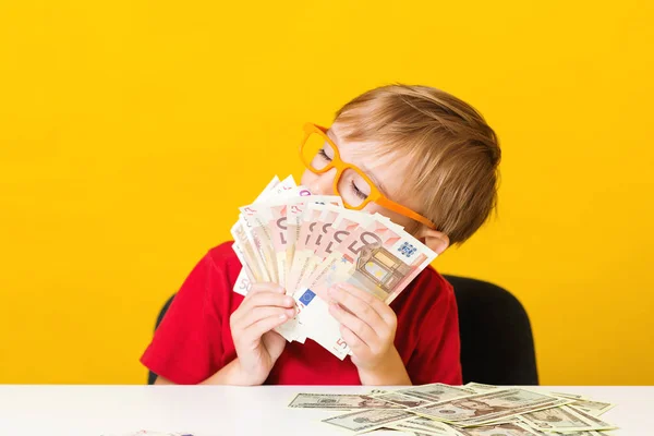 Cute little boy holds a lot of money. Kid save money for future education. Money, finances, insurance and people concept — Stock Photo, Image