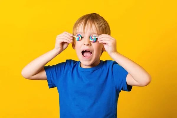 Grappig jongen verlies melktanden. Kind bedekt ogen met lolly 's. Leuke opgewonden jongen over gele achtergrond. Tandenfee concept. — Stockfoto