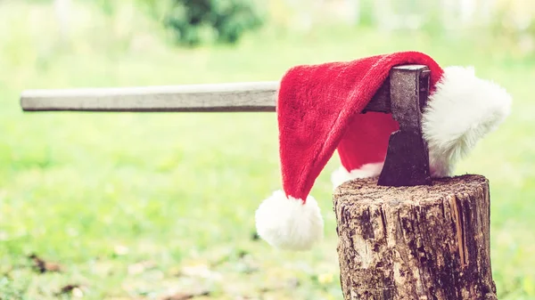 Mikulás kalap és a régi balta a természet hátterében. Karácsonyi ünnepek koncepciója. Karácsonyi vakáció — Stock Fotó