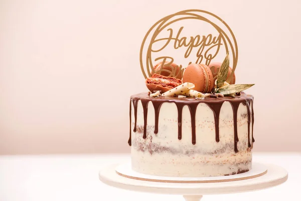 Bolo de aniversário decorado com macaroons dourados e pedaços de chocolate. Elegante bolo nu coberto por chocolate . — Fotografia de Stock