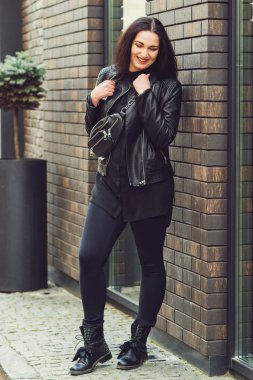 Sokak modası konsepti. Moda hippi kadın dışarıda poz veriyor. Siyah deri ceket giyen seksi bir kız.. 
