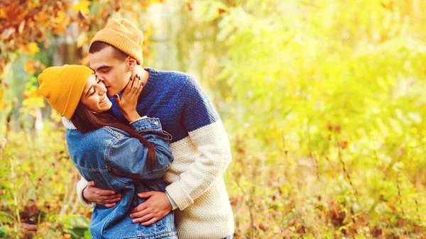 Snygg pojkvän kysser sin tjej i höstparken. Snyggt par njuter av relationen till naturen. Par förälskade. — Stockfoto