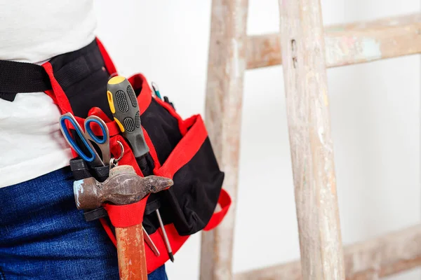 Worker belt with construction tools, closeup. Builder wearing belt with instruments for housework. Isolated on white, copy space. Construction worker with tool belt. House renovation concept.