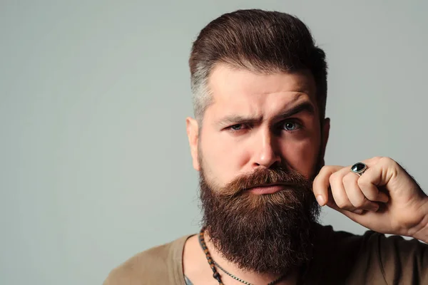 Face portrait of bearded man. Barber shop. Men hairstyle, beard and mustache. Fashion and male beauty. Brutal barber over blue background. Serious young bearded man.