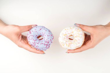 Kadın elleri donut tutuyor, manzarası çok güzel. Kız seçim yapıyor. Senin için tatlı çörekler. Kopya alanı olan bir arkaplan. Minimal tarz, düz yatış. Popüler tatlılar ve tatlılar.