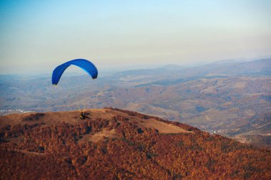 Sonbahar havasında uçan paraglider. Paragliding konsepti. Güzellik doğası Karpat Dağları manzarası. Sonbahar tatili, seyahat. Paraglider sonbaharda dağların üzerinden uçuyor. Ekstrem spor, yaşam tarzı.