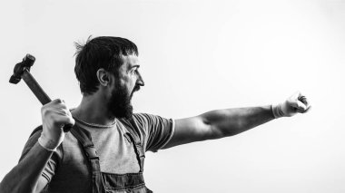 Çığlık atan ustabaşı elinde çekiç tutuyor. Zalim adam çekiç sallıyor. İnşaat işi. Çekiçle çalışan sakallı bir inşaatçı. Profesyonel aletleri olan bir inşaatçı. Siyah ve beyaz.