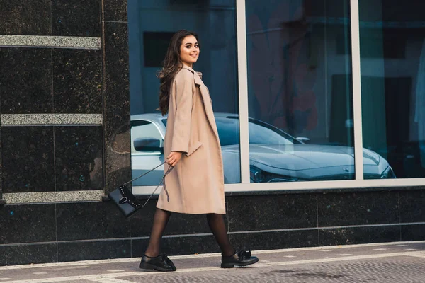 一个时髦的女人走在橱窗前 时尚女孩穿着时髦的外套 人和生活方式 城市街道上的一个时髦的女孩 妇女时尚 — 图库照片