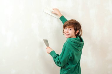 Spatula ile çalışan yakışıklı çocuk. Ev tadilatı. Şirin bir oğul, anne ve babaya odalarını tamir etmeleri için yardım eder. Aletleri olan çocuk. Aile için yeni bir ev.