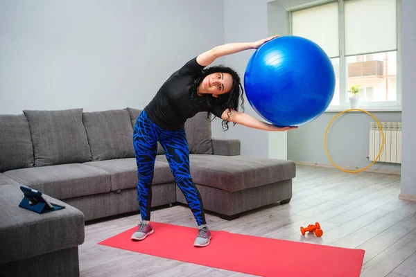身材苗条的女人带着皮球进行健身锻炼 健康的生活方式 家庭锻炼的概念 健身锻炼 女孩在家里训练 穿着运动服的强壮的女运动员 — 图库照片
