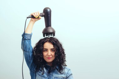 Kıvırcık saçlarını saç kurutma makinesiyle özel difüzör başlığıyla şekillendiren tatlı bir kız. Evde modern saç kurutma makinesi kullanan bir kadın. Kadın kendini kıvırcık saçlı yapıyor. Güzellik ve saç bakımı. Kurutan kadın saçı