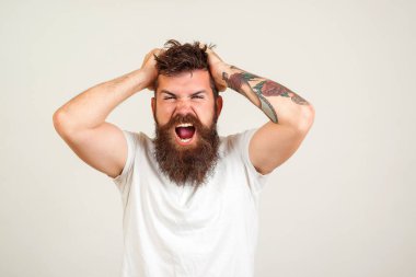 Bağıran ve kızgın bir adam. Beyaz arka planda bağıran sakallı vahşi adam. Yüz ifadesi. Sakallı deli adam. Olumsuz duygular, sorunlar. Stresli adam bağırıyor..