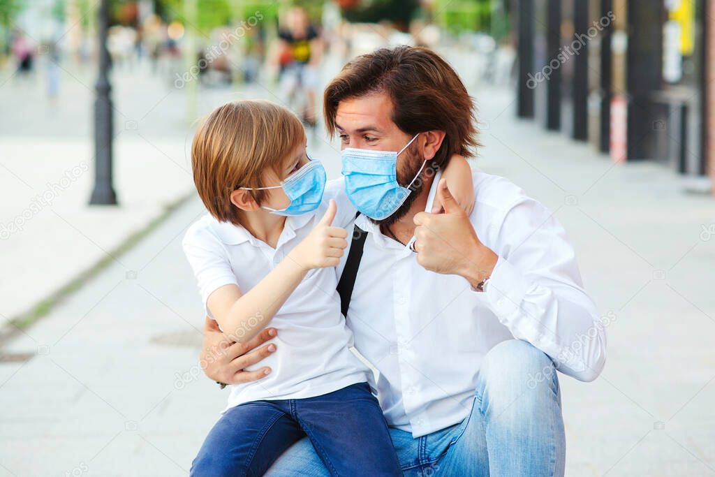 Dad and schoolboy wearing face mask. Schoolboy is ready go to school. Coronavirus pandemic. Family, lifestyle, fashion and quarantine. Father with child in medical mask at city street. Family together.