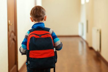 Sırt çantalı okul çocuğunun arka görüntüsü. Üzgün çocuk evine gidiyor. İlkokul, okula dönüş konsepti. Okul zorbalığı konsepti. Eğitim, zorbalık, çatışma, sosyal ilişkiler ve halk konsepti.