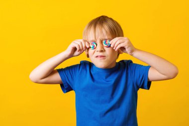 Mutsuz çocuğun gözleri lolipopla kaplıydı. Şekerlerle oynayan bir çocuk. Çocukluk.