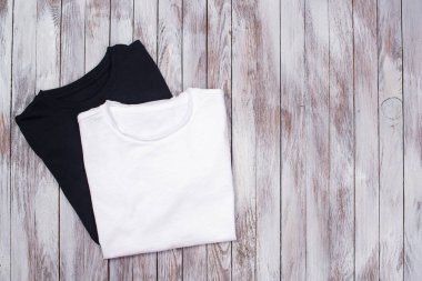 İki boş tişörtle maket. Sunum için ahşap arka planda siyah beyaz tişörtler. Tasarımınız için alanı kopyalayın.