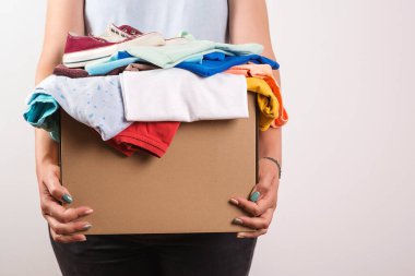 Bağış kutusu tutan bir kadın. Bağış kutusu. Sermaye sosyal etkinliği. Hayırseverlik için kıyafetlerin olduğu karton kutu. Bağış toplayan gönüllü bir kadın. Vermek için bir çanta dolusu kıyafet. Yardım zavallı.