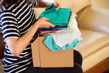 Fakir insanlar için bağış yapan bir gönüllü. Hayırseverlik için kıyafetlerin olduğu karton kutu. Fakire yardım. Bağış kutusu tutan bir kadın. Yoksullar için giysi dolu bir çanta. Sermaye sosyal etkinliği.