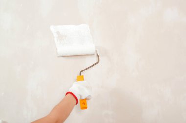 İşçi, duvarı paten fırçasıyla boyuyor. Banner, metin için boşluğu kopyala. El ele tutuşan fırça. Odada duvar boyayan çocuk. İnşaat ve yenileme. Ev yenileme servisi.