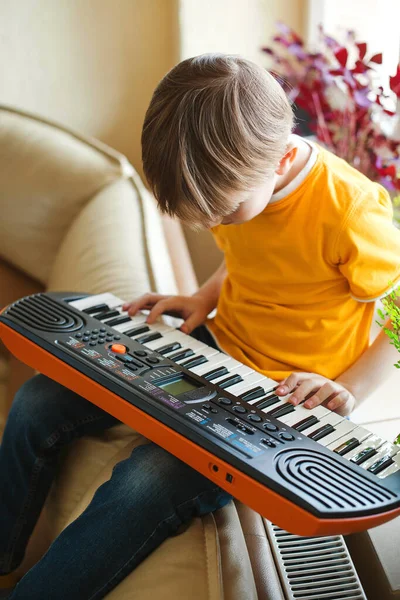 Boy learning to play the synthesizer. Music education and extra-curricular lessons. Development of musical abilities in children. Little kid is playing on a synthesizer at home. Children hobbies