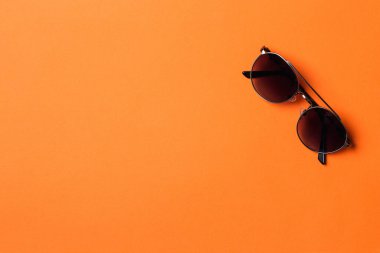 Turuncu arka planda izole edilmiş moda güneş gözlükleri. Yaz modası, alışveriş ve satış. Siyah güneş gözlüğü. Uzayı kopyala Koruma gözleri için modern aksesuar.