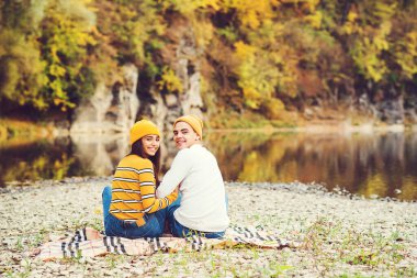 Doğada yürüyen sevgi dolu bir çift. Sonbahar havası. Mutlu adam ve kadın sonbaharda sarılıp öpüşüyor. Sevgi. Açık havada şık bir çift. Moda, insanlar ve yaşam tarzı. Sonbahar kıyafetli şık bir çift..